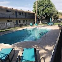 Phoenix apartment for rent - A pool with lounge chairs and a fence in front of a building.