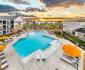 Savannah apartment for rent - A large swimming pool surrounded by lounge chairs and umbrellas at dusk.