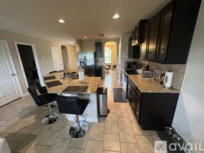 San Antonio house for rent - A kitchen with black cabinets and a granite countertop.