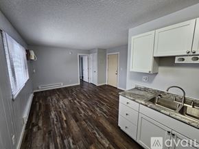 La Crosse apartment for rent - A kitchen with wooden floors and white cabinets.