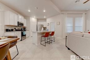 Temple house for rent - A modern kitchen with white cabinets and a dining area with red chairs.