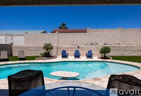 Lake Havasu City house for rent - A pool with a table and chairs in front of a wall.