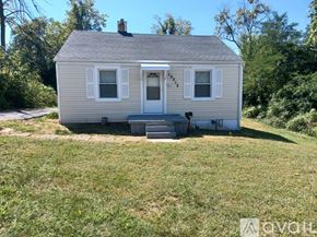 Saint Ann house for rent - A small house with a grey roof and white trim is surrounded by greenery.