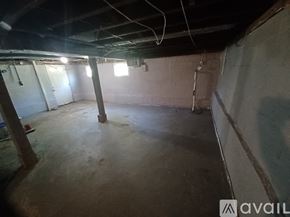 Saint Ann house for rent - A spacious basement with concrete floors and exposed pipes.