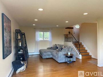 Stillwater house for rent - A living room with a grey couch and a staircase.