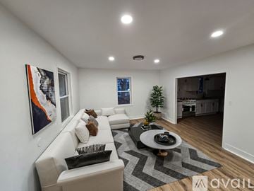 Brownstown house for rent - A modern living room with a white sofa, a coffee table, and a painting on the wall.
