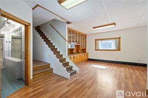 Pittsburgh house for rent - A spacious room with wooden flooring and a staircase leading to another level.