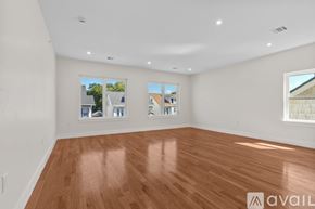 Newark apartment for rent - A spacious room with wooden flooring and two windows.