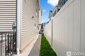 Newark apartment for rent - A narrow alley with a white fence on the right and a building with a window and air conditioner on the left.