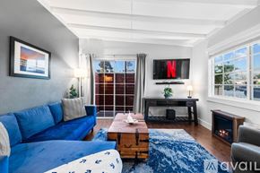 San Diego house for rent - A bedroom with a large bed, a desk with a lamp, and a wardrobe with clothes hanging on it.