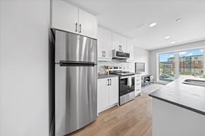 Ottawa apartment for rent - A modern kitchen with a stainless steel refrigerator and wooden flooring.