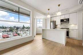 Chilliwack apartment for rent - A kitchen with white cabinets and a large window overlooking a street.