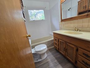 Michigan City house for rent - A bathroom with a toilet, sink, and mirror.