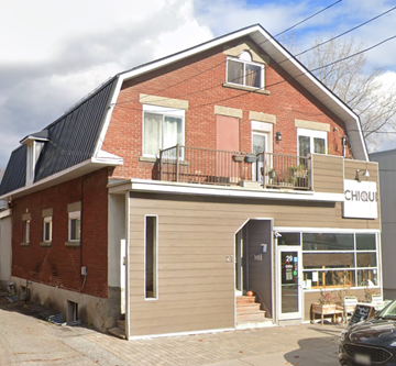 Ottawa apartment for rent - A red brick building with a black metal roof and a sign that says "CHIQU".