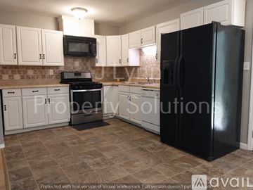 Orangeburg house for rent - A black refrigerator in a kitchen with white cabinets.