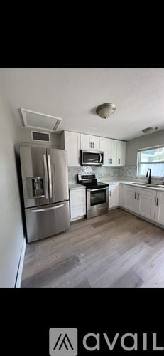 Clearwater house for rent - A kitchen with a refrigerator, microwave, oven, and cabinets.