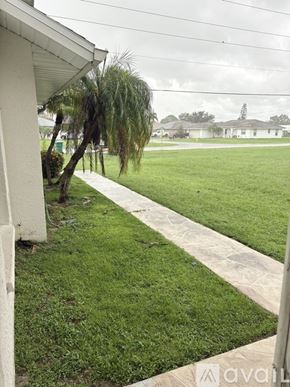 Punta Gorda apartment for rent - A palm tree is leaning over a concrete walkway.