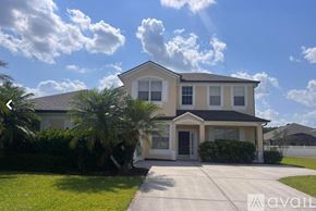 Kissimmee house for rent - A house with a driveway and palm trees in front.