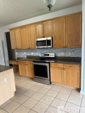 Kissimmee house for rent - A kitchen with wooden cabinets and a black countertop.