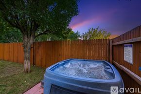 Dallas house for rent - A hot tub sits in a backyard surrounded by a wooden fence.