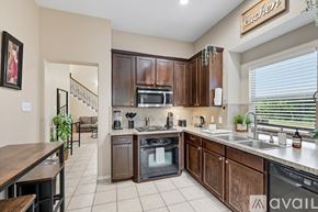 Dallas house for rent - A kitchen with brown cabinets and a stainless steel dishwasher.
