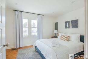 Charlottesville house for rent - A bedroom with a large bed and a window with curtains.