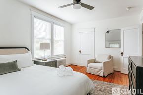 Charlottesville house for rent - A bedroom with a large bed, a chair, and a ceiling fan.