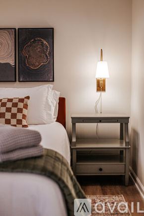 Charlottesville apartment for rent - A bedroom with a bed, nightstand, and two wall art pieces.