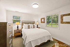 Savannah house for rent - A bedroom with a large bed, a nightstand with a lamp, and a window with blinds.