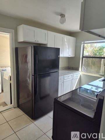 Daytona Beach apartment for rent - A black fridge in a kitchen with white cabinets.