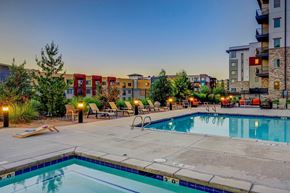 Sandy apartment for rent - A pool surrounded by chairs and trees with buildings in the background.