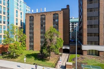 Calgary apartment for rent - A person is walking on a sidewalk in front of a brick building.