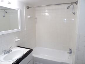 Dallas apartment for rent - A white bathroom with a sink, mirror, and bathtub.