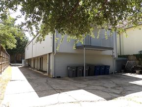 Dallas apartment for rent - A long building with a garage door is surrounded by trees.