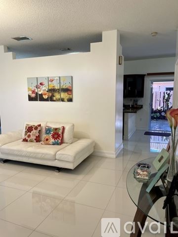 Doral house for rent - A living room with a white couch and a painting on the wall.
