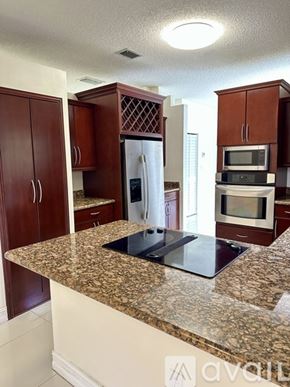 Doral house for rent - A kitchen with brown cabinets and a granite countertop.