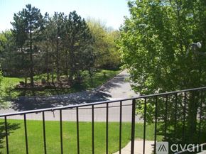 Coon Rapids apartment for rent - A view from a balcony looking down at a tree-lined path.