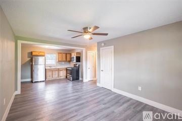 Houston apartment for rent - A kitchen with a refrigerator, sink, and stove is visible from the living room.
