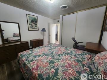 Los Angeles house for rent - A bedroom with a floral bedspread and a mirror on the wall.