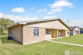 Belton house for rent - A house with a beige exterior and a brown roof is surrounded by a grassy lawn.