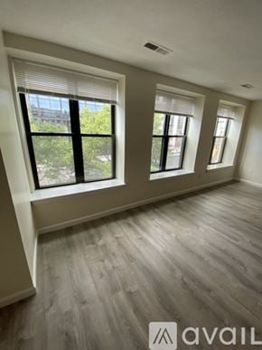 Boston apartment for rent - A room with wooden flooring and three windows.
