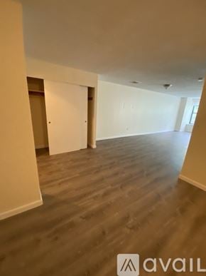 Boston apartment for rent - A room with wooden flooring and white walls, with a logo that reads "avaiL" in the bottom right corner.