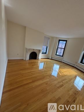 Boston apartment for rent - A room with wooden flooring and a fireplace with a window on the right side.