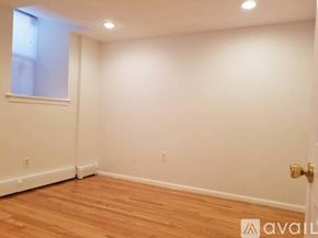 Boston apartment for rent - A room with wooden flooring and white walls, with a window on the left and a door on the right.