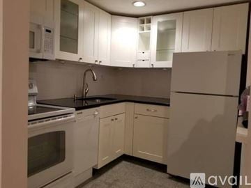 Boston apartment for rent - A kitchen with white cabinets and a black countertop.