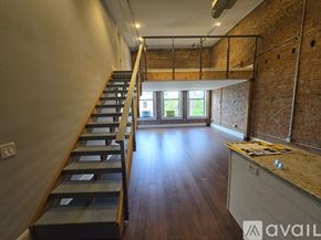 Kalamazoo apartment for rent - A long staircase with wooden steps and railings leads to a bright room with a window.