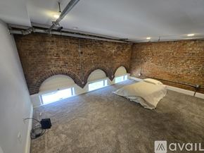 Kalamazoo apartment for rent - A room with a brick wall and a bed with a white cover.