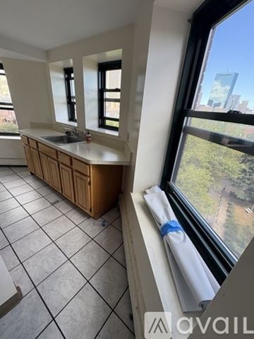 Boston apartment for rent - A kitchen with a wooden cabinet and a window overlooking a cityscape.