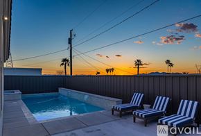 Lake Havasu City house for rent - Two striped lounge chairs sit on a patio next to a pool.