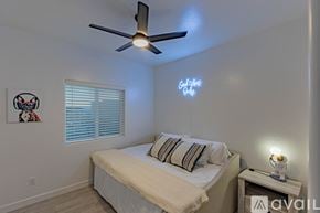 Lake Havasu City house for rent - A bedroom with a bed, a ceiling fan, and a nightstand with a lamp.